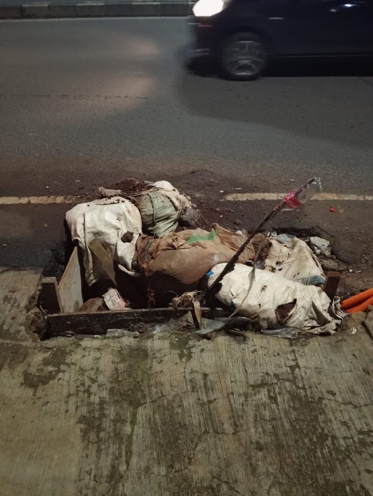 Teks Alt: Kondisi jalan Swadaya Raya Larangan Tangerang yang rusak dan berlubang akibat bekas galian kabel optik di depan Apotek Syifa, mengancam keselamatan pengendara motor pada Senin 19 Januari 2026.