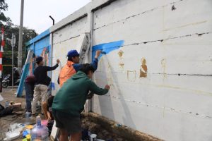 Seniman lokal sedang menyelesaikan lukisan mural bertema penghijauan pada dinding ruang publik di Kecamatan Larangan Tangerang sebagai persiapan kompetisi menyambut HUT ke-33 Kota Tangerang pada Januari 2026.