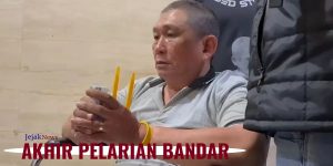 Tersangka Erwin Iskandar alias Koko Erwin dengan pengawalan ketat personil bersenjata lengkap saat tiba di Bandara Soekarno-Hatta menggunakan kursi roda pasca penangkapan di Tanjung Balai.