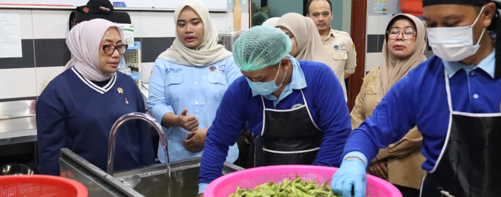 Menteri PPPA Arifah Fauzi sedang berdialog dengan para ibu pekerja di Dapur SPPG Medan sambil meninjau standar kebersihan pengolahan makanan.