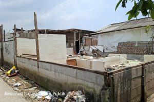 Alat berat ekskavator sedang meratakan bangunan semi-permanen di lahan TPU Kamal Kalideres dengan pengawalan ketat petugas gabungan.