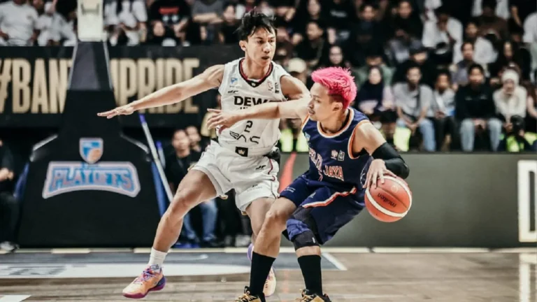 Andakara Prastawa melakukan manuver lay-up melewati penjagaan ketat Joshua Ibarra di dalam area paint Dewa United Arena.