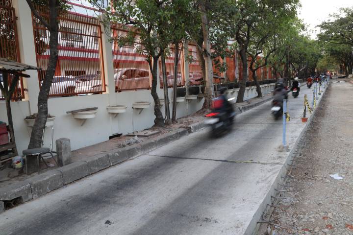 Alat berat ekskavator dan pekerja Dinas PUPR Kota Tangerang melakukan pemadatan tanah dan pengecoran semen di ruas Jalan Marsekal Suryadarma Neglasari.